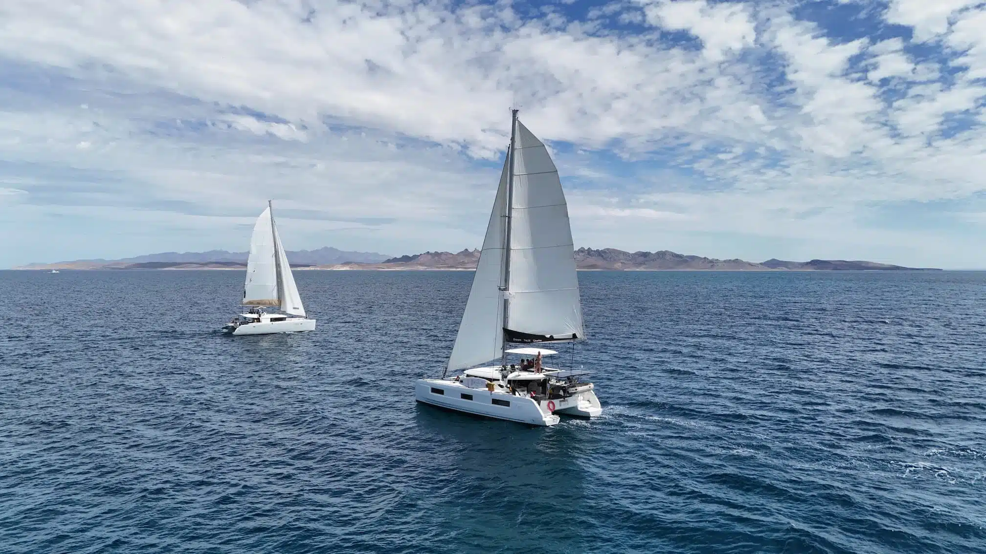 Catamaran sailing in the Sea of Cortez with desert mountains of Baja California Sur