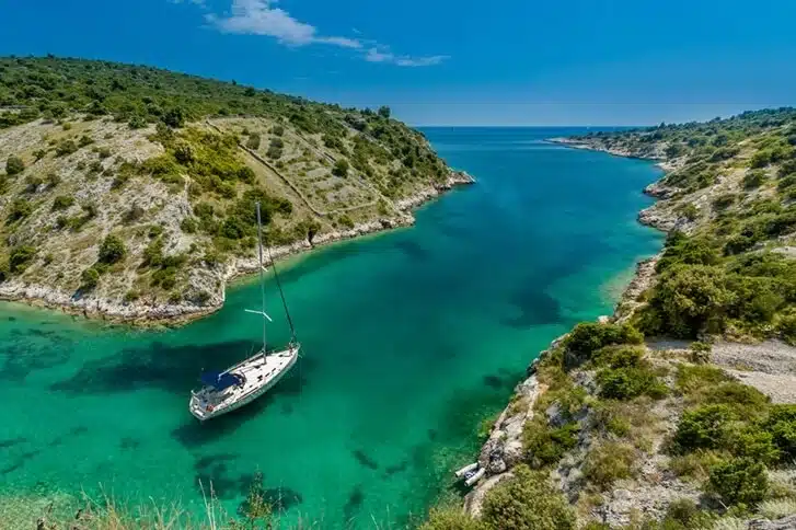 Sailboat anchored in an emerald cove in Croatia, aerial view
