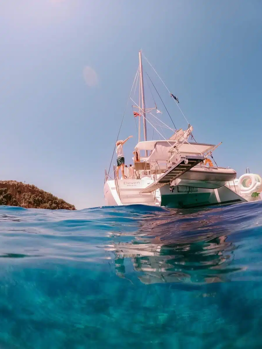 Swimmer's view of a catamaran at anchor in clear blue water