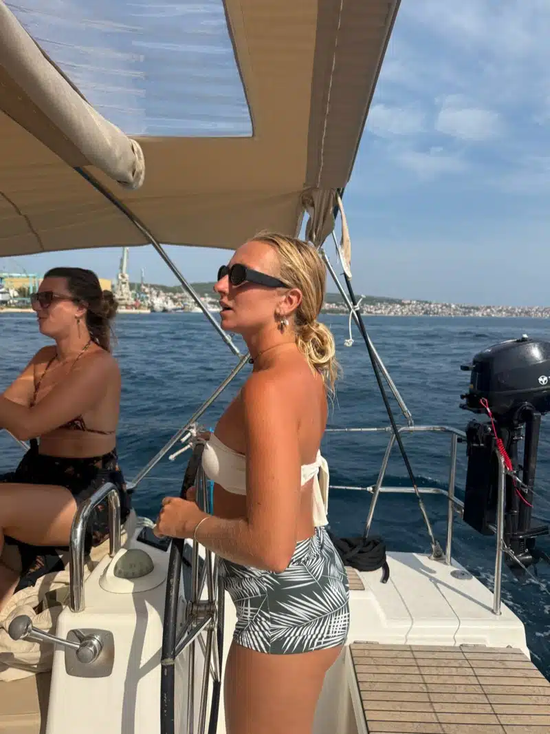 Two sailors at the helm of a yacht under a shade bimini